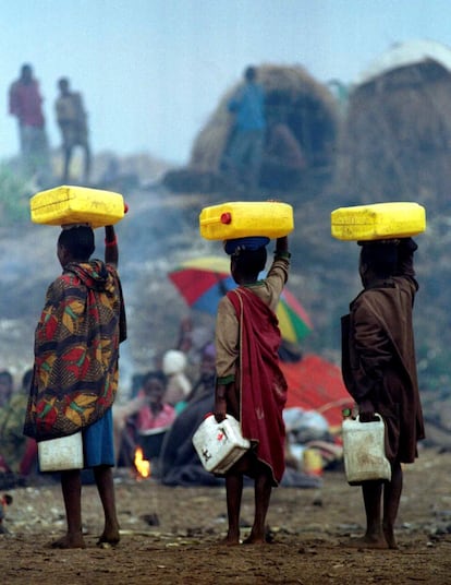 Tres jóvenes refugiados transportan bidones de agua distribuidos por militares franceses en el campamento de refugiados de Mugunga, cerca de Goma, el 13 de agosto de 1994.