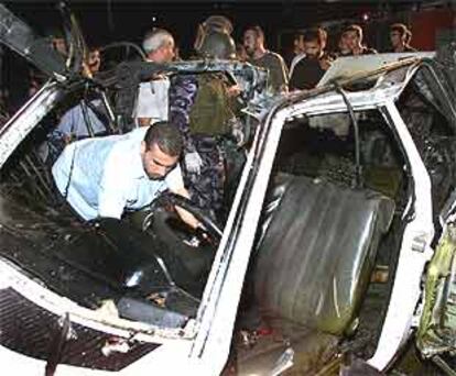 Un policía palestino inspecciona los restos del coche destruido por una bomba en Gaza.