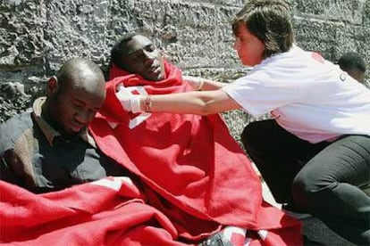 Una voluntaria de Cruz Roja tapa a algunos de los integrantes de la última patera llegada a Tarifa.