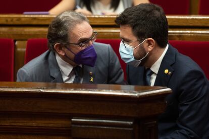 A la derecha, el presidente catalán, Pere Aragonès, conversa con el conseller de Economía y Hacienda, Jaume Giro, durante el pleno del Parlament este jueves.