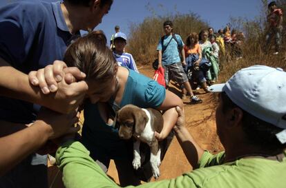 Uma mulher carrega seu cachorro enquanto é ajudada a subir um morro em Talcahuano.