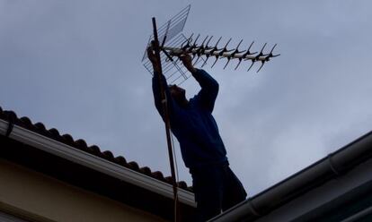 Un hombre revisa la antena de una vivienda.