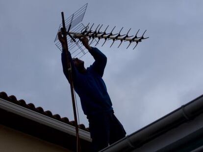 Un hombre revisa la antena de una vivienda. 