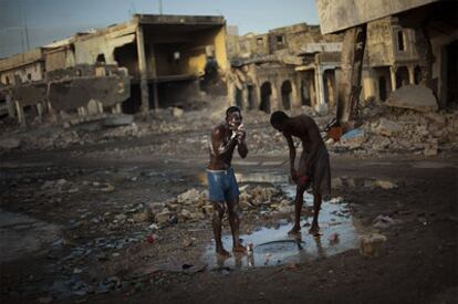 Dos jóvenes se lavan con el agua de una alcantarilla en el centro de Port-au-Prince (Haití).