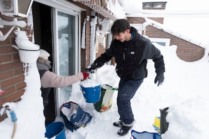 Una mujer y su hijo tratan de aligerar el peso de la nieve sobre la terraza de su vivienda, este sábado en Alcorcón.