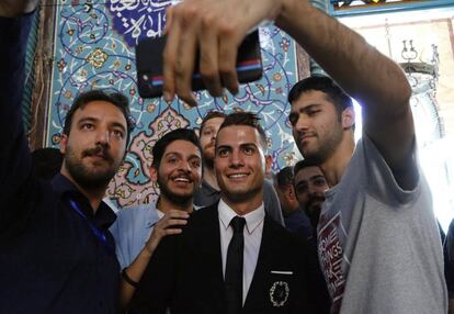 Iraníes posan para un selfi con Reza Alireza Lou (c), un joven que presenta un gran parecido con el delantero portugués del Real Madrid Cristiano Ronaldo, después de votar en un colegio electoral de Teherán.