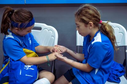 Candela y Nicole rezan en el banquillo mientras continúa el partido en la pista.

