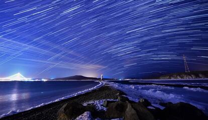 Lluvia de estrellas Gemínidas durante su pico, en el cielo nocturno sobre el faro de Tokarevsky en el cabo de Egersheld en la isla de Russky en el mar de Japón.