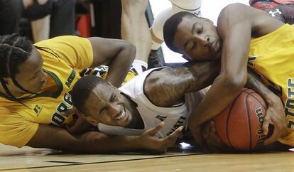 Farad Cobb, del Cincinnati, en el centro, lucha por la pelota con Jeff Shor, a la izquierda, y Alex Long, a la derecha, del Norfolk durante el partido de baloncesto disputado ayer en Cincinnati.