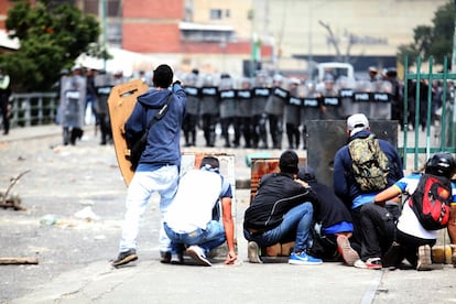 Manifestantes se protegen frente al cordón policial en El Paraíso (Caracas).