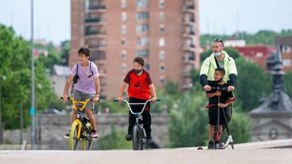 Dos niños en bici y un hombre con otro menor en patinete pasean por Madrid Río en la capital este sábado.