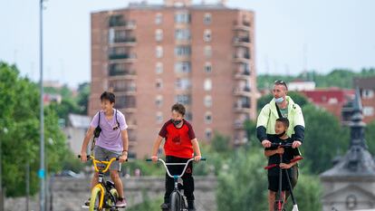 Dos niños en bici y un hombre con otro menor en patinete pasean por Madrid Río en la capital este sábado.