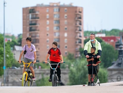 Dos niños en bici y un hombre con otro menor en patinete pasean por Madrid Río en la capital este sábado.