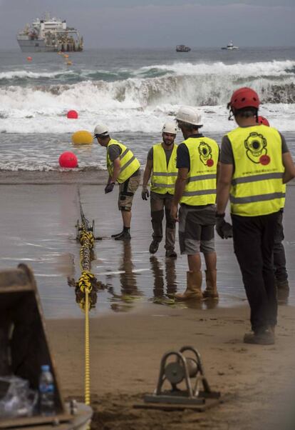 Con este amarre, arranca el tendido de la nueva infraestructura, que operará Telxius (Telefónica) y que con su 6.600 km de longitud, ocho pares de fibra óptica y una capacidad de 160 Tbps, será el de mayor capacidad que jamás haya cruzado el Atlántico y también el primero que conecte Estados Unidos con el sur de Europa. En la imagen, los operarios supervisan los trabajos del anclaje.