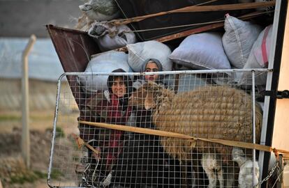 Dos mujeres sirias se desplazan en la parte trasera de un camión de camino al campamento de Deir al-Ballut, en la frontera con Turquía.