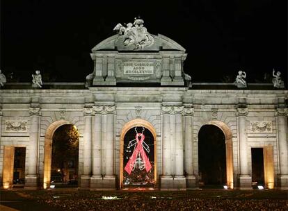 El colectivo de lesbianas, gays, bisexuales y transexuales de Madrid ha colocado un gran lazo rojo, diseñado por Devota & Lomba en la puerta de Alcalá de la capital para conmemoran el Día Mundial contra el sida.