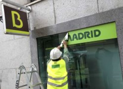 Un operario quita el logotipo de Caja Madrid para poner el de Bankia. 