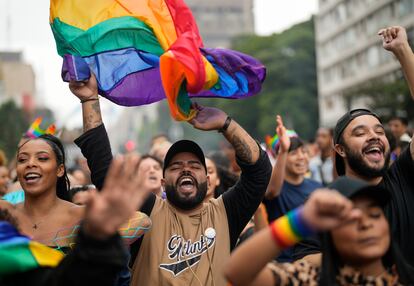 Un joven brinca mientras ondea una bandera del orgullo gay.