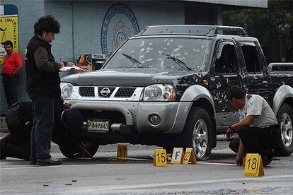 Dos agentes examinan un coche acribillado por más de 200 balas, tras un asesinato en Guatemala.