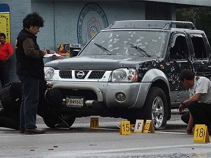 Dos agentes examinan un coche acribillado por más de 200 balas, tras un asesinato en Guatemala.