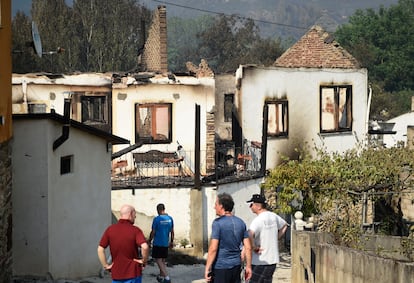 Los aldeanos observan las casas quemadas tras un incendio forestal en A Veiga de Cascalla (Orense), el 19 de julio de 2022.
