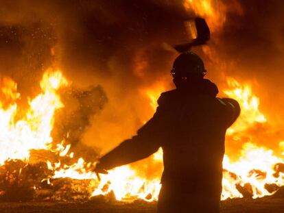 Un trabajador tira un elemento a una barricada durante un velatorio nocturno simbólico convocado por la fábrica de Alcoa, en San Cibrao, el pasado 28 de noviembre.