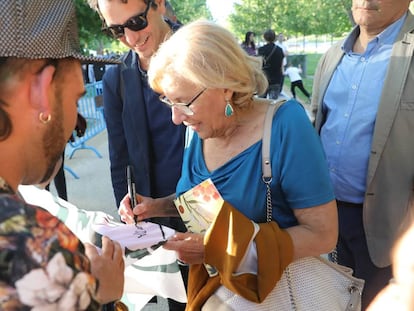 La alcaldesa de Madrid Manuela Carmena firmando un autógrafo en una de las pancartas de su candidatura ayer a orillas del Manzanares (Madrid).