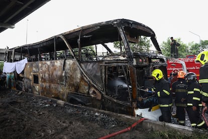 Los bomberos trabajan para extinguir las llamas después de que un autobús se incendiara en las afueras de Bangkok, en Tailandia, este martes.