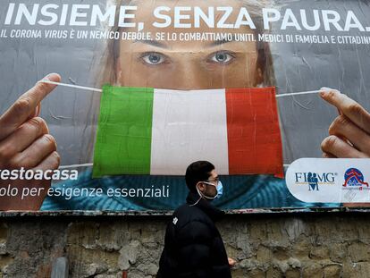 Un hombre con mascarilla pasa por delante de un cartel con indicaciones sobre cómo protegerse del virus, en las calles de Nápoles, el sábado.