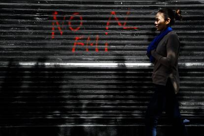 Una mujer camina frente a un grafiti contra el Fondo Monetario Internacional durante la huelga de 24 horas en Buenos Aires (Argentina).