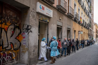 Personal sanitario atiende a personas haciendo cola para realizarse una PCR frente al centro de salud Universidad en Malasaña, en Madrid el día 20.