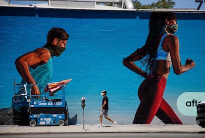 Un peatón pasa frente a un mural de 'runners' con mascarilla, pintado en el Boulevard de Melrose, en West Hollywood, California (EEUU).