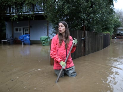 mujer intenta despejar el área de su domicilio tras el desporde del Río San Lorenzo en Felton Grove, California