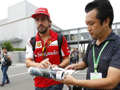 Fernando Alonso firma un autógrafo en el paddock.