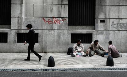 Una mujer camina frente a tres trabajadores que almuerzan en Buenos Aires.