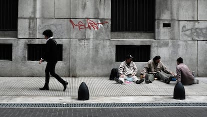 Una mujer camina frente a tres trabajadores que almuerzan en Buenos Aires.