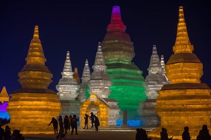 Esculturas y grandes construcciones de hielo, adornadas con luces de colores, maravillan a los visitantes que acuden a Harbin (noreste de China) y que abarrotan sus calles pese a unas temperaturas de hasta 25 grados bajo cero. En la imagen, un grupo de turistas visitan las esculturas iluminadas.