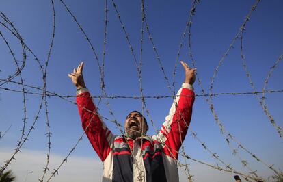 Un manifestante muestra el saludo de los "cuatro dedos" tras un alambre de espino instalado en la entrada de la Academia de Policía, donde iba a continuar el juicio al expresidente Mohamed Mursi, en El Cairo (Egipto).