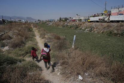 Una mujer y su hija caminan de vuelta del colegio cerca del Río de los Remedios, un canal de desagüe del Estado de México.