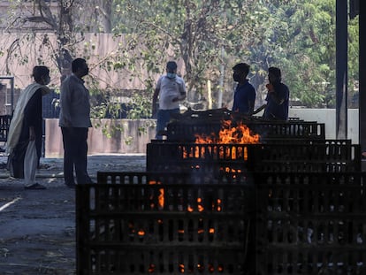 Unos familiares de fallecidos a causa de la covid-19, delante de las piras funerarias en la India, el 11 de mayo de 2021 en Ahmedabad.
