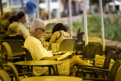 Una persona leyendo un libro frente al mar en Calella de Palafrugell, el 24 de julio.
