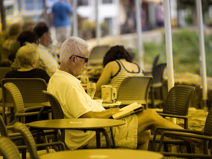 Una persona leyendo un libro frente al mar en Calella de Palafrugell, el 24 de julio.