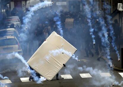 Jóvenes se cubren de gases lacrimógeno detrás de un colchón durante la manifestación en contra de la propuesta de la legislación laboral francesa en Nantes.