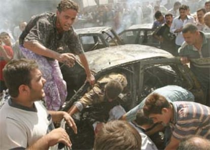Iraquíes tratan de extraer de un coche el cuerpo de uno de los fallecidos en el atentado.