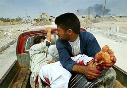 Un civil iraquí ayuda a un amigo herido en la parte trasera de una furgoneta en los alrededores de Basora.