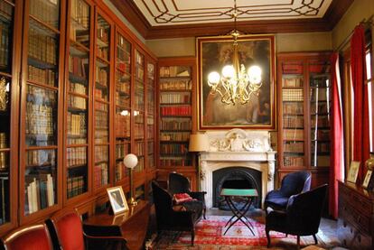 Biblioteca del Palau Moxó con una chimenea que lleva un escudo de los Moxó, lámpara modernista y libros.