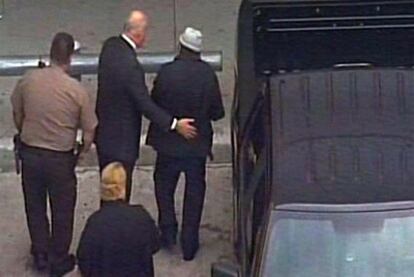 Noriega, con sombrero, es conducido al avión en el aeropuerto de Miami.