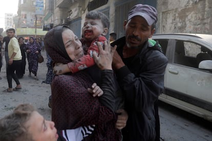 A Palestinian woman cries as she carries her wounded son following an Israeli airstrike in Bureij refugee camp, Gaza Strip,
