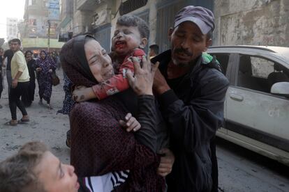 A Palestinian woman cries as she carries her wounded son following an Israeli airstrike in Bureij refugee camp, Gaza Strip,