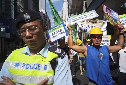 Un trabajador sujeta unas pancartas durante la manifestación del 1 de Mayo por las calles de Hong Kong (China).